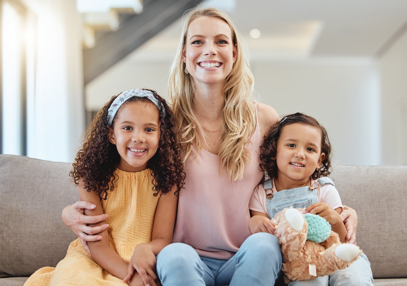 Adoption, Portrait and Mother with Kids on Sofa in Living Room, Smiling and Hugging. Love, Foster Care and Happy Mom Bonding with Girls, Having Fun or Enjoying Quality Time Together in  Home.